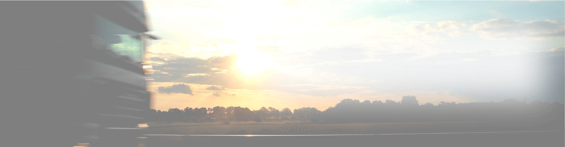 Weichgezeichnetes Bild eines LKW der bei Sonnenaufgang über die Autobahn fährt