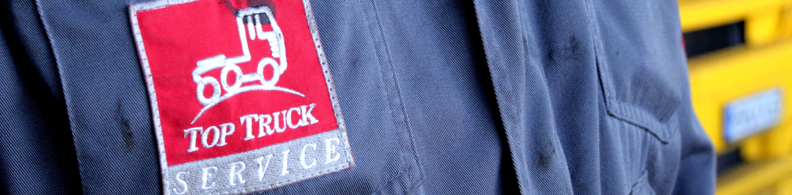 Mitarbeiter vor einem Truck mit aufgesticktem Top Truck Logo auf der Jacke