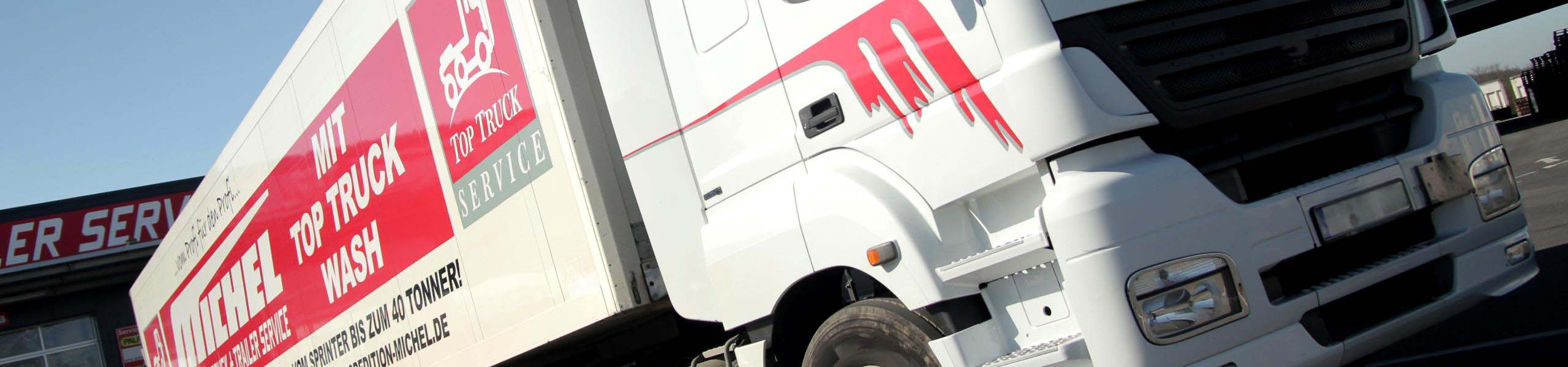 Weißer Truck mit individueller Beklebung und Top Truck Audruck im System-CI in rot